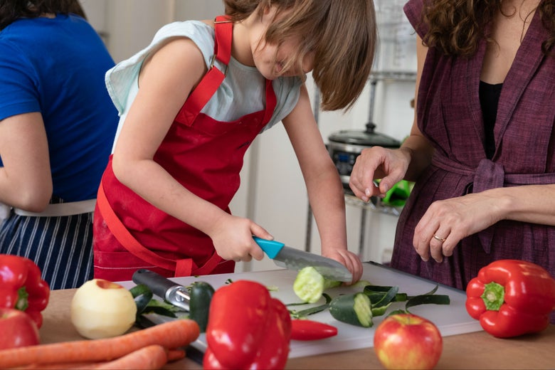 kid in apron chopping vegetables